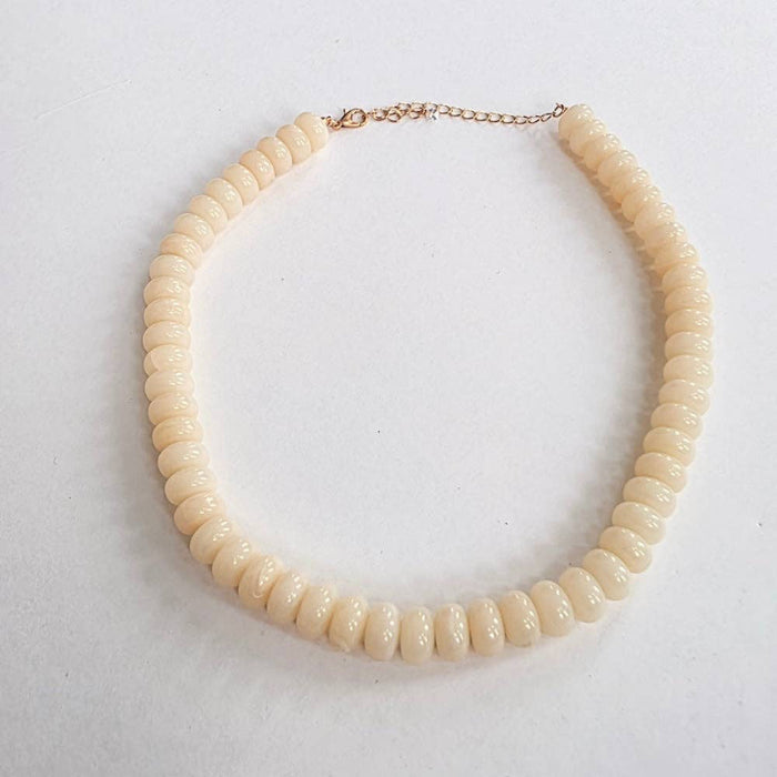 Beige beaded necklace on a light gray background