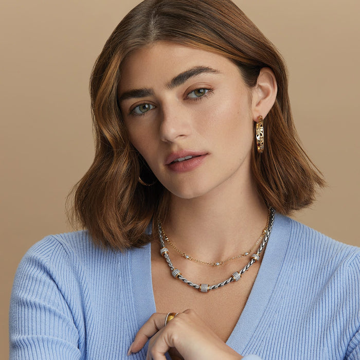 Model wearing Brighton gold-plated hoop earrings paired with layered silver and gold necklaces with crystal accents