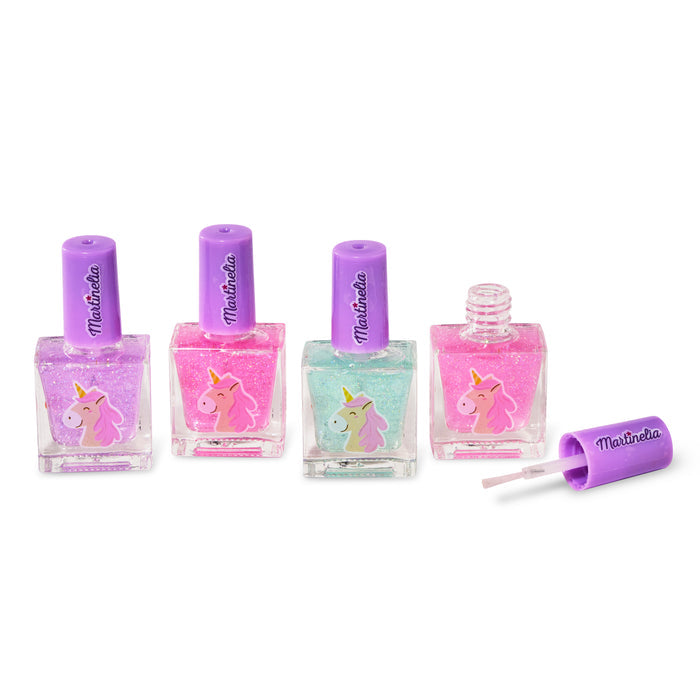 The Martinelia Little Unicorn Nail Polish Set includes four pink and green glitter bottles, each with a unicorn design and signature purple cap—one bottle open with the brush beside it. A magical Martinelia nail polish set for kids.