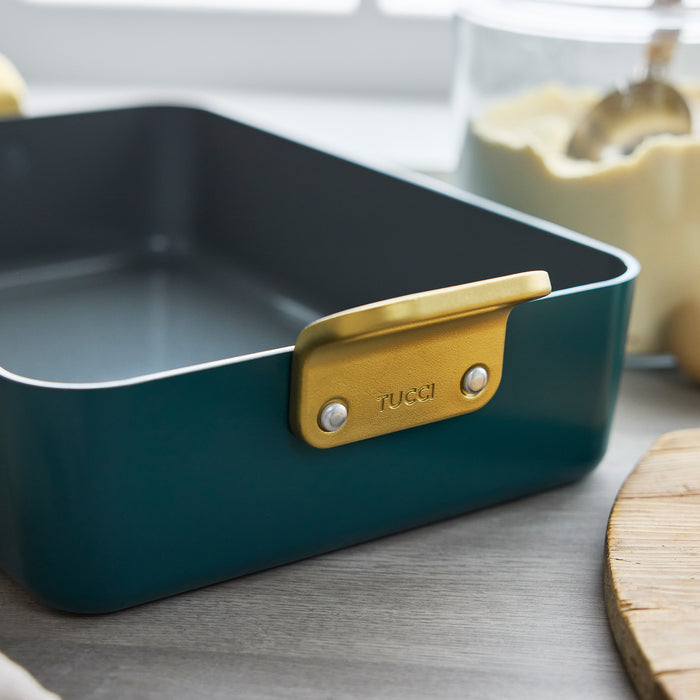 Venetian Teal ceramic lasagna pan with a gold handle on a kitchen counter.