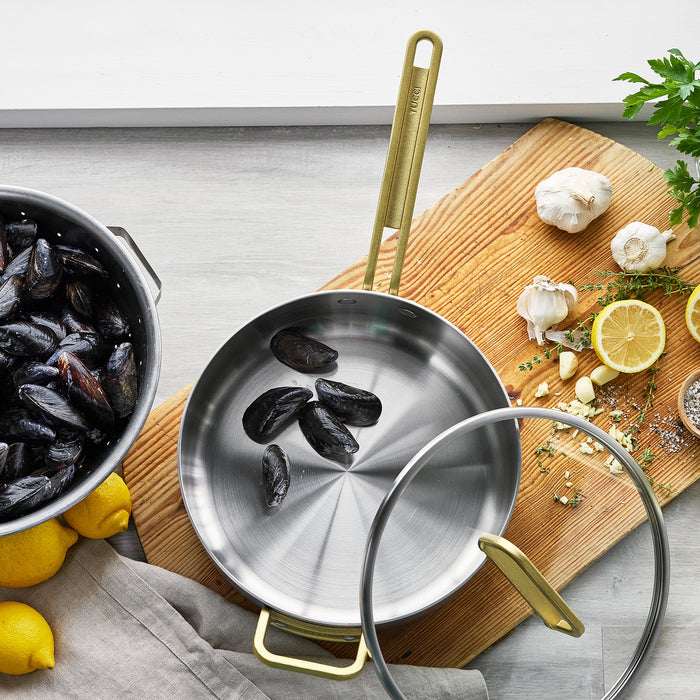 Stainless steel sauté pan with lid, 4-quart size, filled with cooked mussels and fresh herbs.