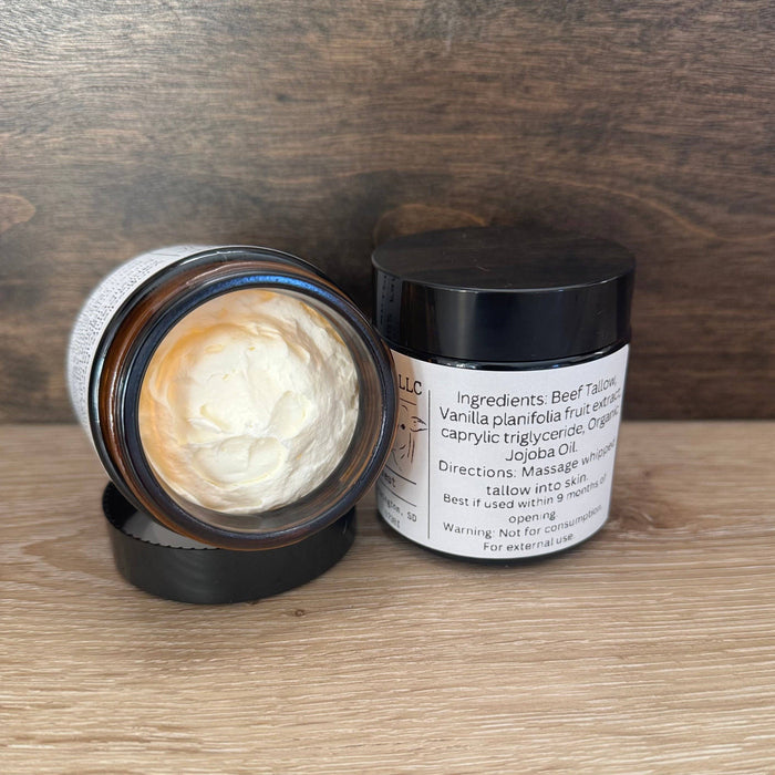 Open jar of cream with a black lid on a wooden surface
