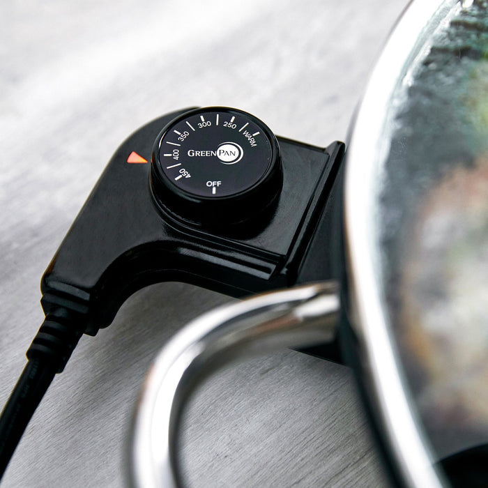 Electric skillet temperature control dial set to 150°F beside a silver metal handle.