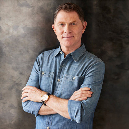 Man in light denim shirt stands beside stainless steel chefs pan with glass lid.