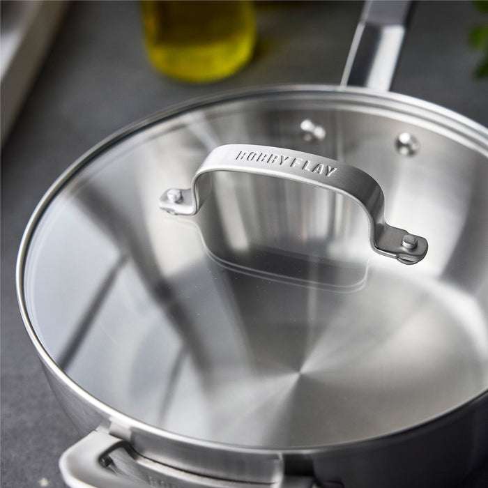 Stainless steel chef’s pan with lid sitting on a gray kitchen counter.