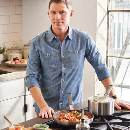 Man in a blue shirt cooking on a stove with stainless steel Bobby Flay by GreenPan cookware set.