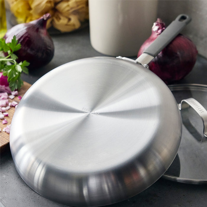 Stainless steel pan upside down on a countertop with onions, parsley, and a wooden chopping board nearby.