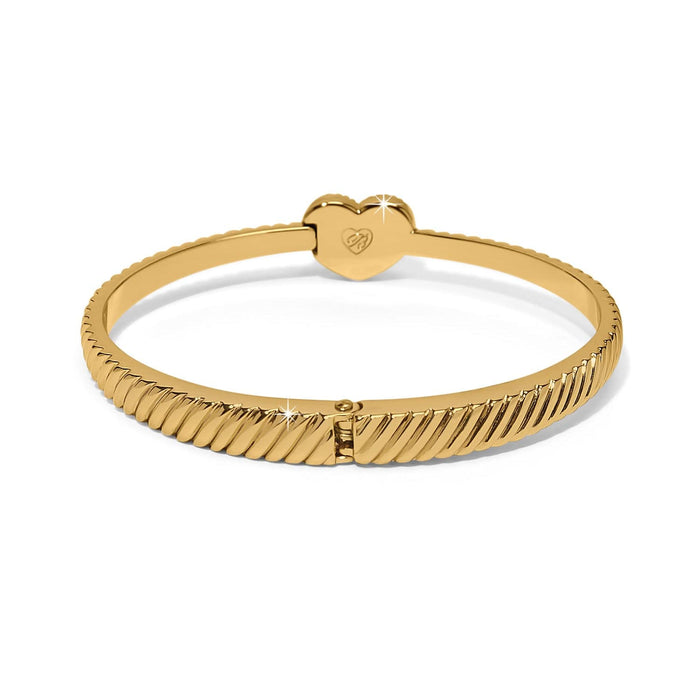 Brighton bangle bracelet with ribbed gold-tone band and engraved heart-shaped hinge clasp on a white background