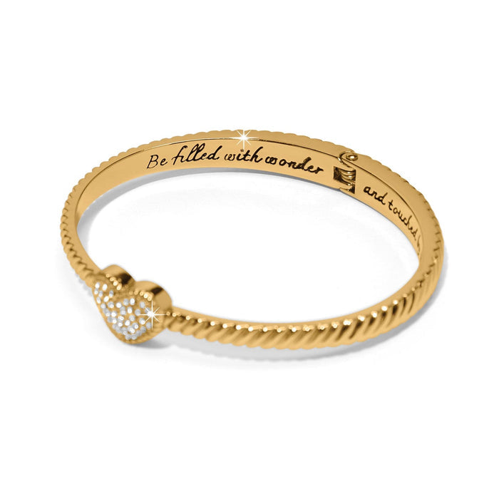 Brighton bangle bracelet with twisted gold-tone band, crystal pavé heart accent, and engraved inscription on a white background