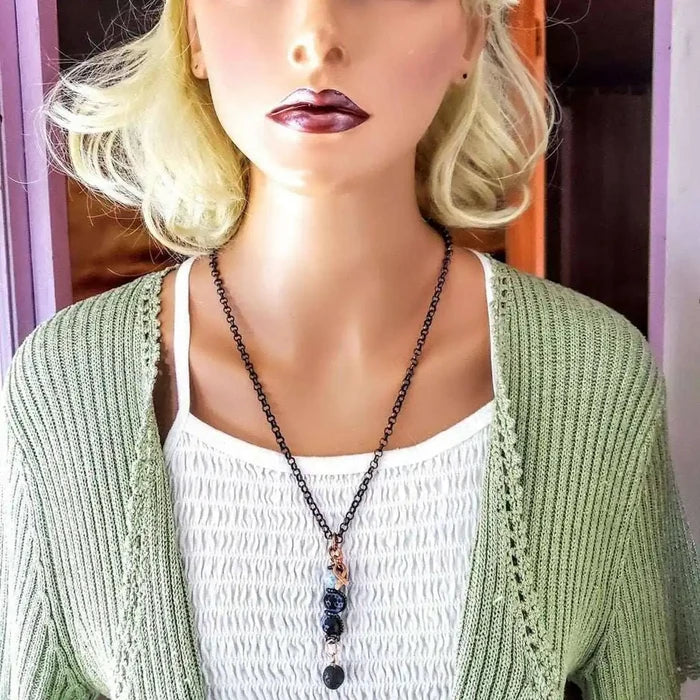 Child Abuse Awareness Agate Necklace With Lava Rock Bead displayed on a mannequin wearing a green cardigan.
