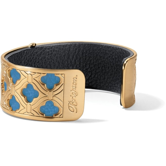 Brighton cuff bracelet with gold-plated quatrefoil openwork design, turquoise accents, and black leather interior on a white background