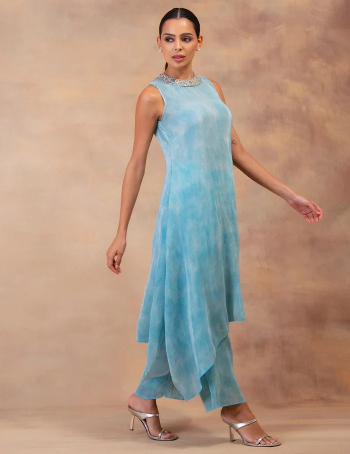 Model wearing the 'CLOUD DRIFT' tunic drape-dress set with matching pants, crafted in micro-pleated georgette satin with gold foil detailing in Singapore.