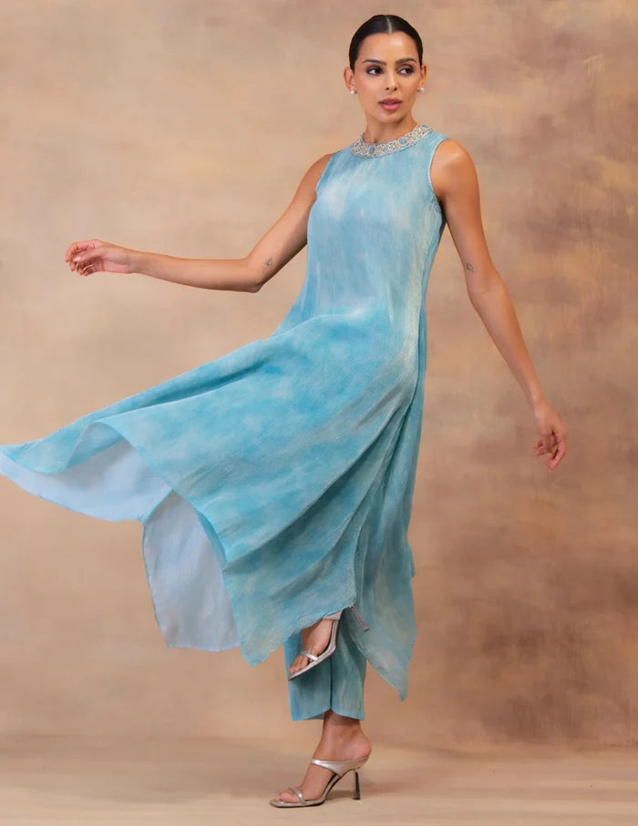 Model wearing the 'CLOUD DRIFT' tunic drape-dress set with matching pants, crafted in micro-pleated georgette satin with gold foil detailing in Singapore.
