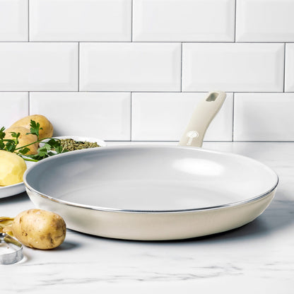 Cream white ceramic nonstick 12-inch frypan on white countertop with potatoes and parsley beside it.