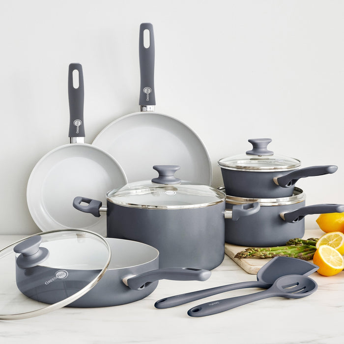 Charcoal gray 12-piece ceramic cookware set with glass lids and utensils arranged on a kitchen counter.