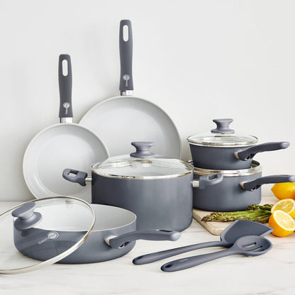 Charcoal gray 12-piece ceramic cookware set with glass lids and utensils arranged on a kitchen counter.