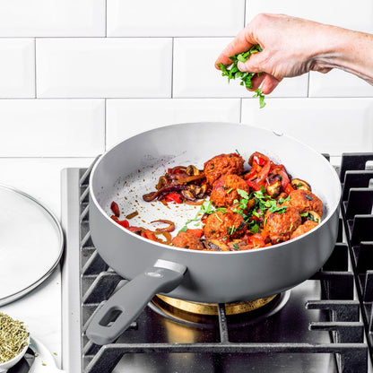 Herbs being sprinkled onto veggie meatballs in a charcoal gray Dover Ceramic Nonstick pan from a 12-piece set.