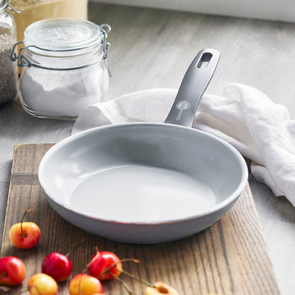 Charcoal gray ceramic 12-piece cookware set on a board with cherries and baking ingredients nearby.