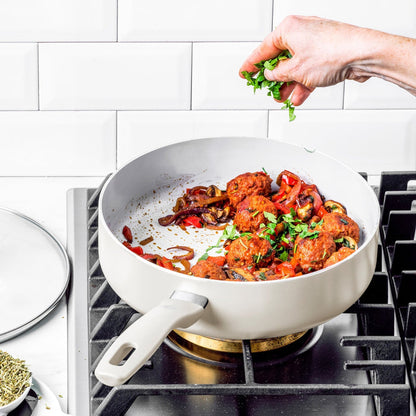 Cream white Dover ceramic cookware set with food inside, topped with fresh herbs; 12 pieces are visible.