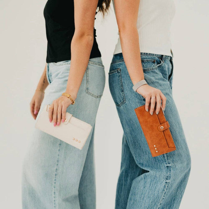 Two people wearing light blue jeans holding a beige clutch and brown wallet against a plain background.