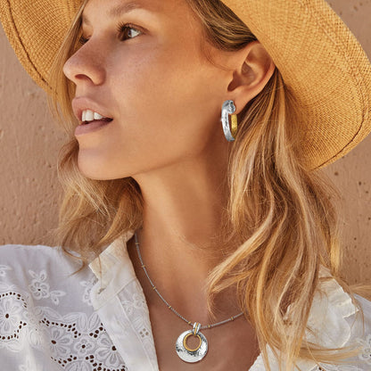 Model wearing Brighton two-tone hammered hoop earrings paired with a matching silver and gold circle pendant necklace