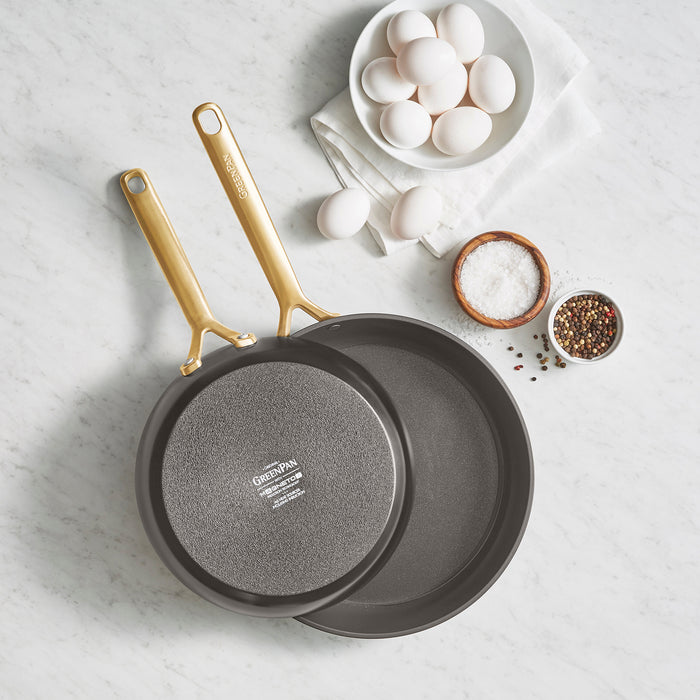 Two ceramic nonstick frypans, 9.5 and 11, with champagne handles on a white marble countertop.