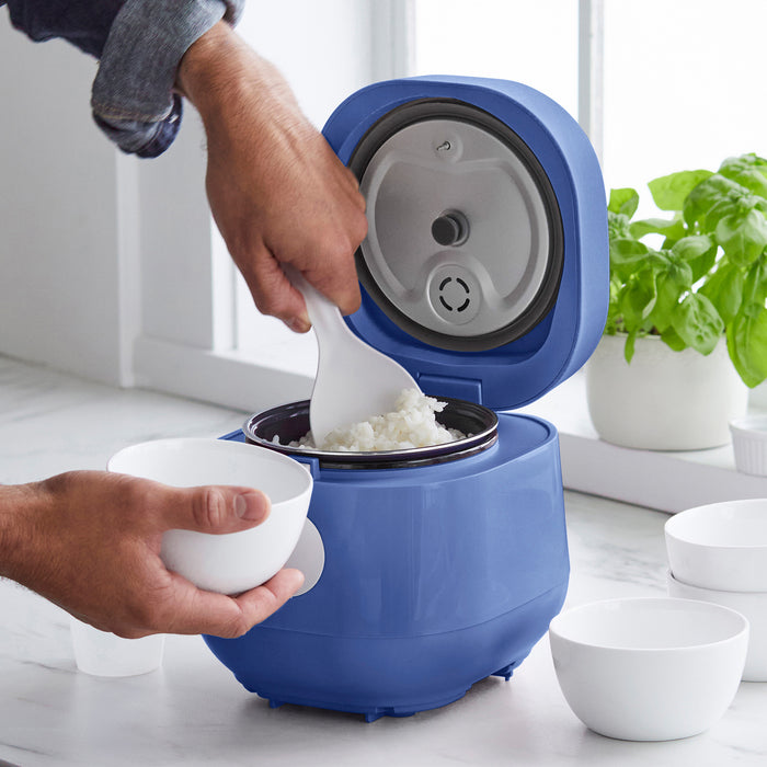 Blue GreenLife 4-cup rice cooker on a counter as rice is scooped into a white bowl.