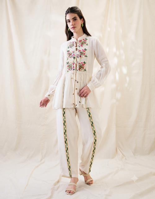 White Gulzaar Appliquéd Peplum Top with front tie-ups paired with straight linen pants, offering an elegant and refined contemporary silhouette.
