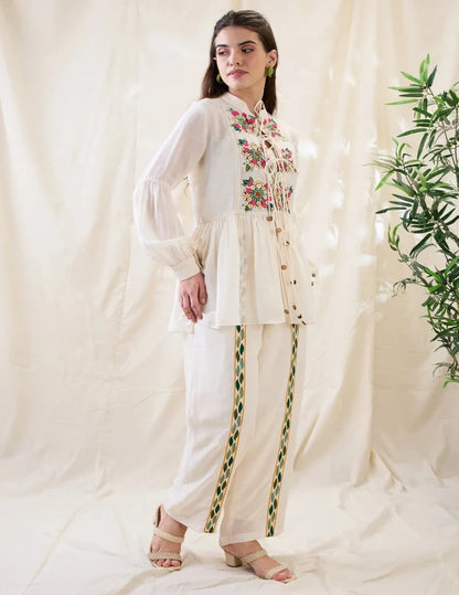 White Gulzaar Appliquéd Peplum Top with front tie-ups paired with straight linen pants, offering an elegant and refined contemporary silhouette.