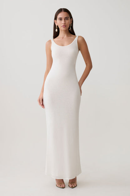 Woman wearing a white scoop neck jersey maxi dress.