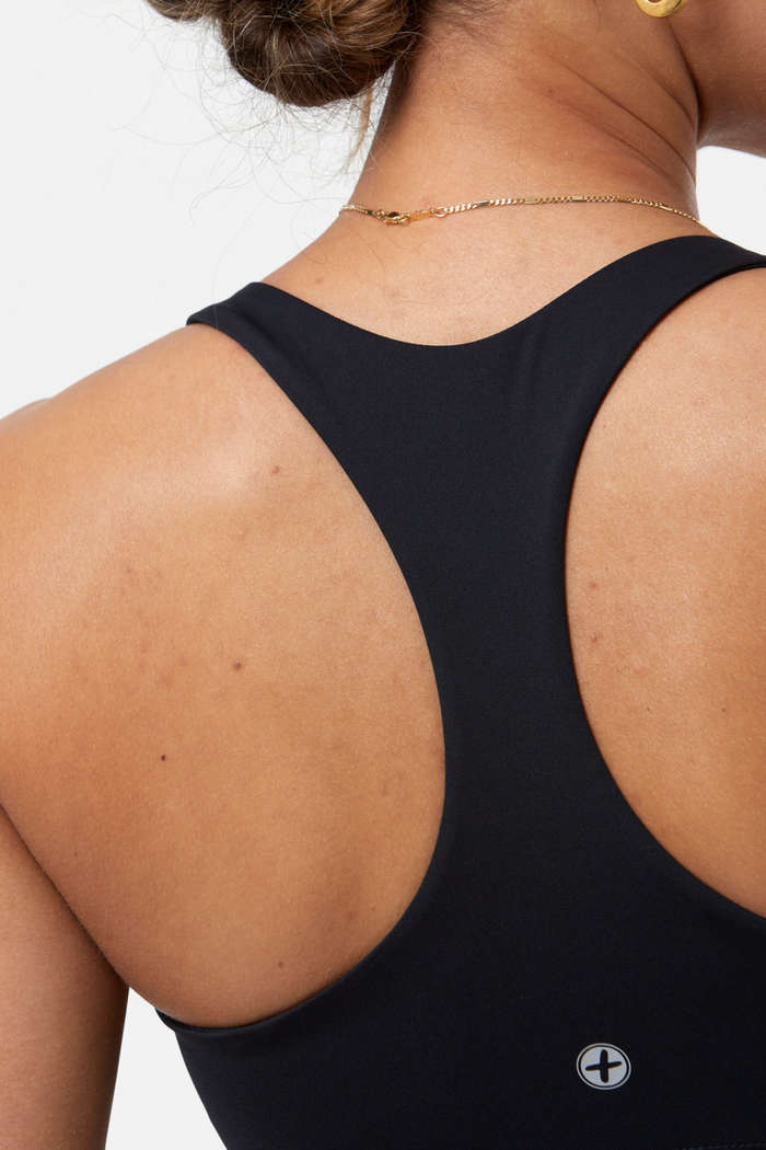 Close-up of a woman wearing Gym+Coffee Relentless Bra Black showing racerback design Shop Gym+Coffee at Dotique