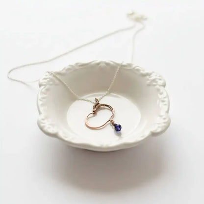 Hammered Copper Butterfly Wing Child Abuse Survivor Necklace on a delicate chain in a decorative dish.