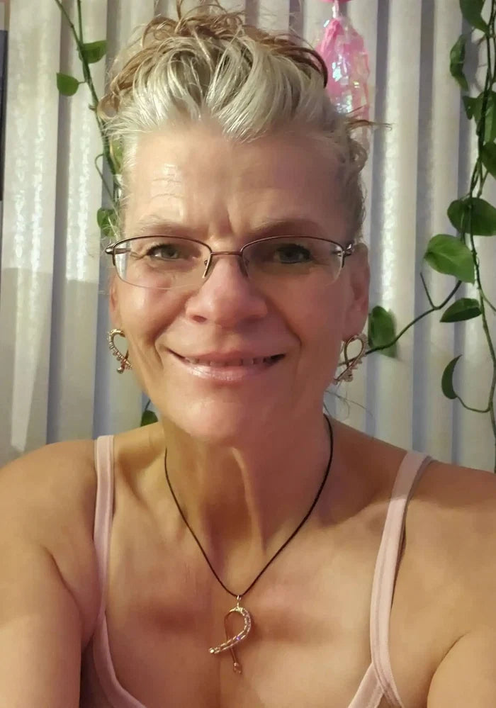 A woman wearing Handmade Copper Silver Pink Crystal Ribbon Jewelry Set with earrings and necklace, smiling in a softly lit room.