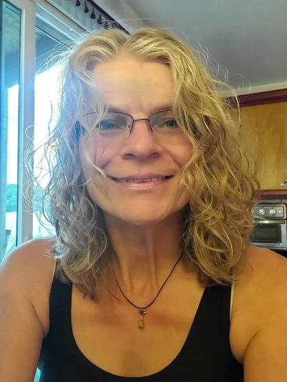 Handmade silver crystal pineapple leather necklace worn by a woman with curly hair and glasses.