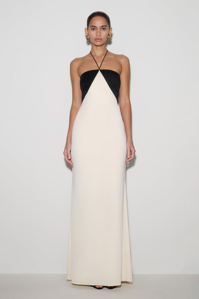 Woman wearing a black and white halter neck dress on a plain background