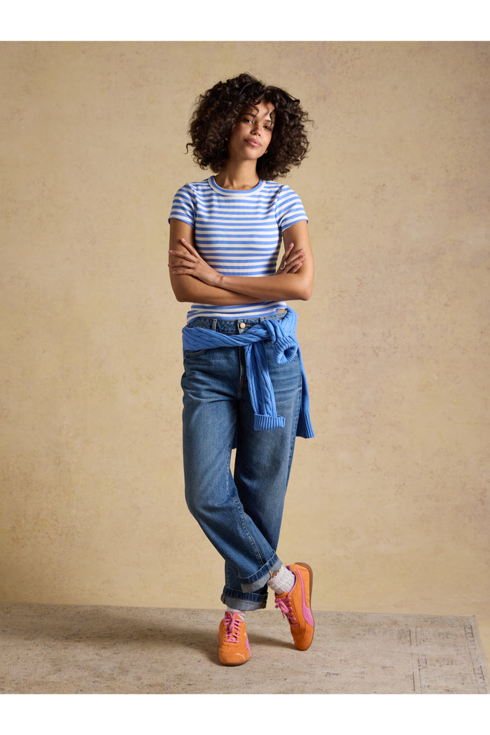 Woman wearing a Joules H77966 Sophie Ribbed T-Shirt – Blue Stripe, featuring casual jeans and sneakers. Shop Joules at Dotique.