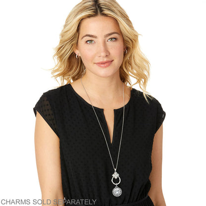 Model wearing a Brighton silver-plated long pendant necklace with floral medallion and round engraved charm.