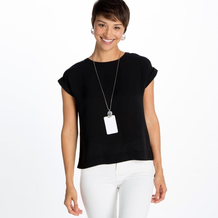 Model wearing a Brighton long pendant necklace with silver-plated rectangular tag and ornate scrollwork drop earrings