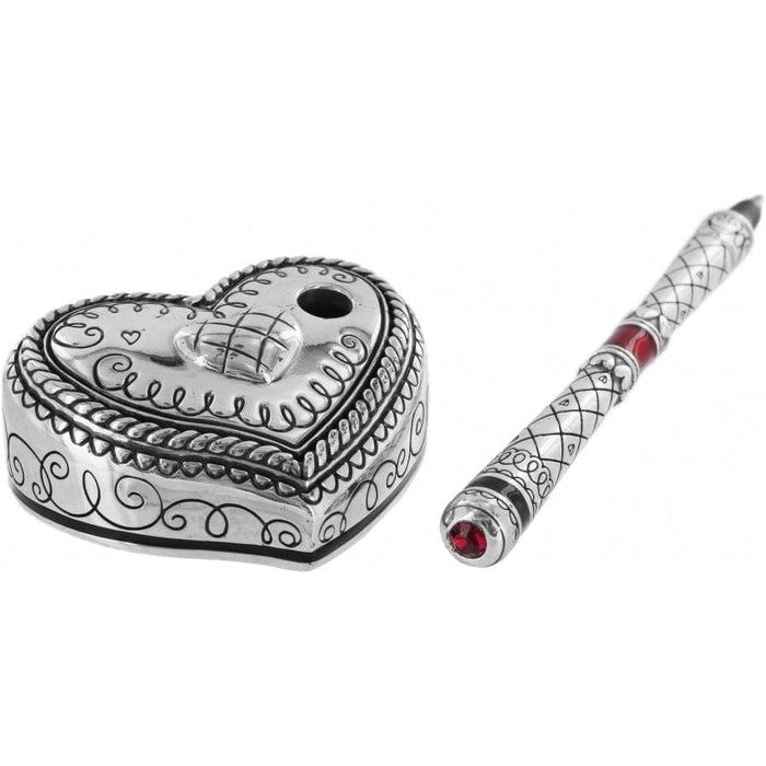 Brighton heart-shaped trinket box with silver-plated scrollwork and matching pen with red crystal accents on a white background