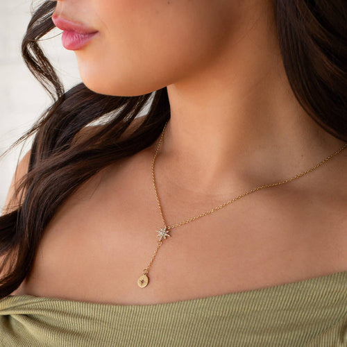 Close-up of a woman wearing a gold necklace with a star pendant.
