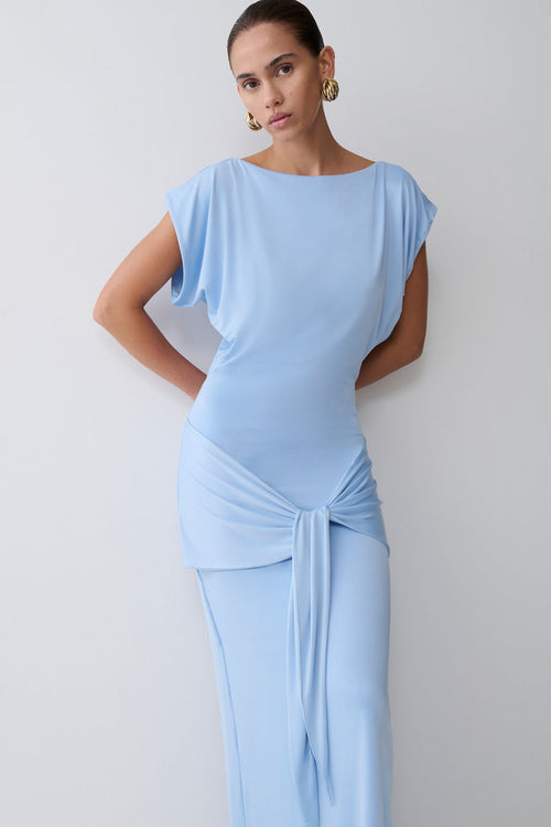 Woman wearing a light blue dress against a plain background