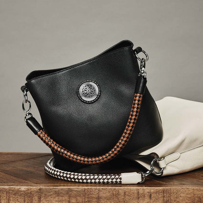 Brighton black leather handbag styled with a white leather bag and braided straps on a wooden surface