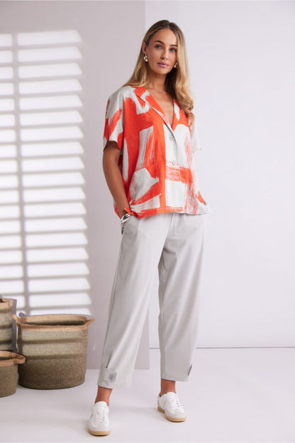 Model wearing Naya NPA26179 Slim Leg Trouser With Tab At Hem Ash paired with an orange graphic blouse, shop Naya at Dotique.