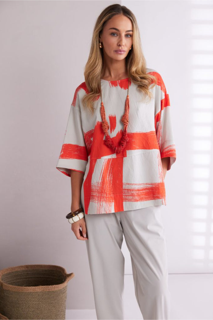 Model wearing Naya NPA26179 Slim Leg Trouser With Tab At Hem Ash paired with an abstract orange and beige top, shop Naya at Dotique.