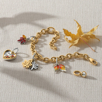 Brighton two-tone charm bracelet styled with maple leaf charms and dried autumn leaves on woven fabric