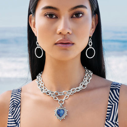 Model wearing a Brighton silver-plated layered chain necklace with blue heart pendant paired with silver hoop earrings