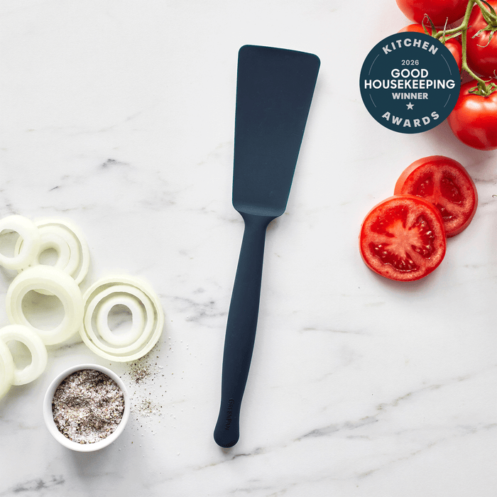 Blue silicone burger turner on marble with sliced onions, tomatoes, peppers, and an award badge.