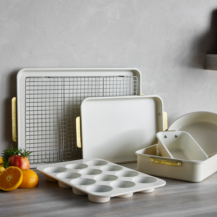 Cream quarter sheet pan on gray counter, surrounded by assorted fruit and matching white bakeware pieces.