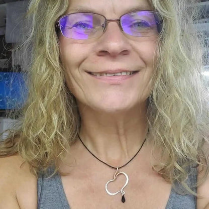 Sculpted Silver Butterfly Wing Child Abuse Survivor Necklace worn by a smiling woman with curly hair.