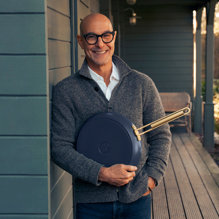 Man in glasses smiling, holding a blue ceramic nonstick frypan with lid.